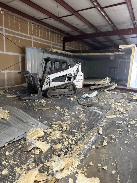 Skid steer clearing debris inside a commercial freezer building during demolition