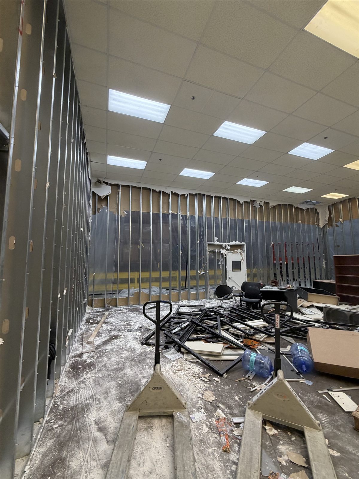 Interior metal-stud wall removed to framing with debris staged during warehouse demolition